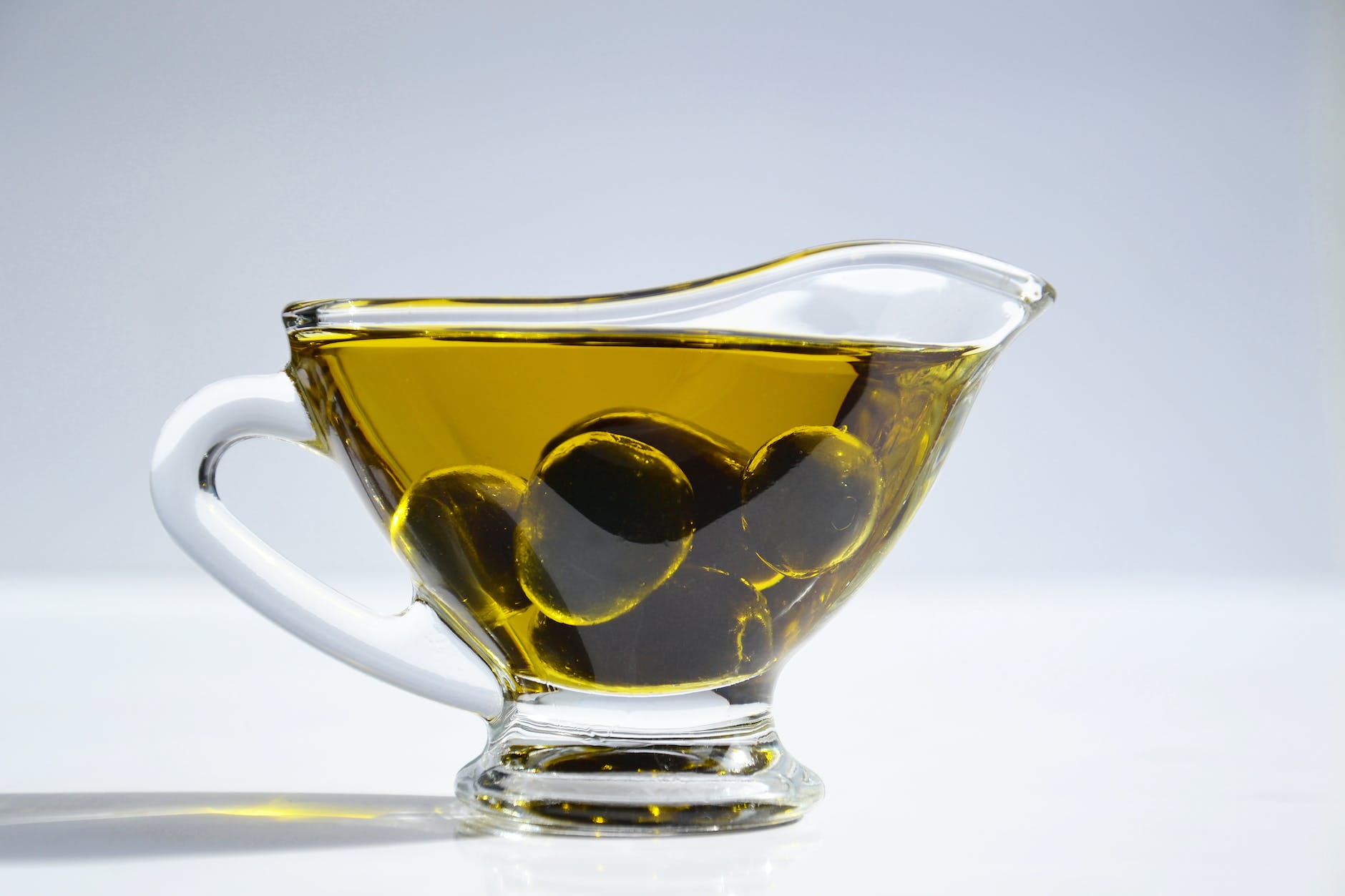 photo of olives on cup of olive oil